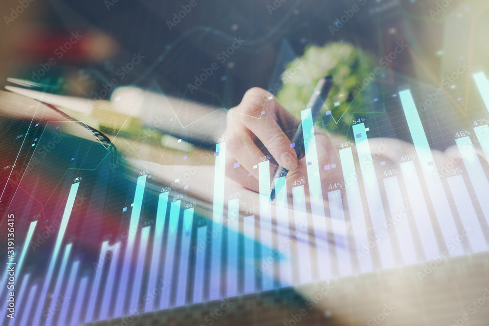 Financial forex graph displayed on hands taking notes background. Concept of research. Multi exposure