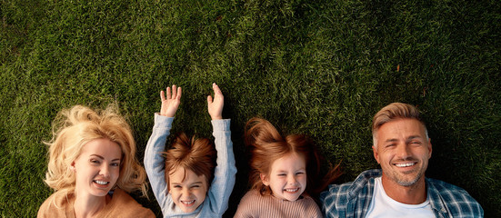 Keep calm and love your family. Happy family of four lying on green grass