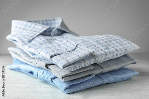 Stack of classic shirts on white wooden table
