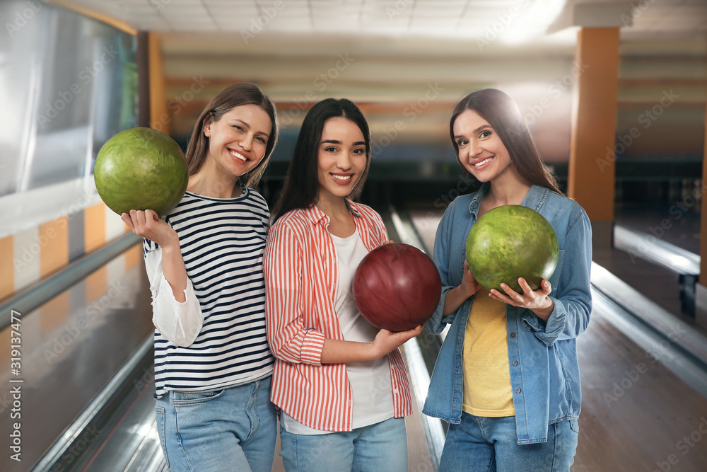 Fototapeta premium Group of young women with balls in bowling club
