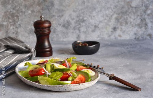 Vitamin salad with avocado, egg, cherry tomatoes on a concrete background.