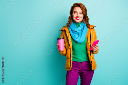 Photo of funny lady hold hot coffee mug beverage smart phone telephone walk street wear casual yellow overcoat scarf trousers green jumper isolated teal color background