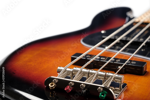 Close Up to the bridge and body part of Sunburst 4 string jazz bass guitar isolated on white background.