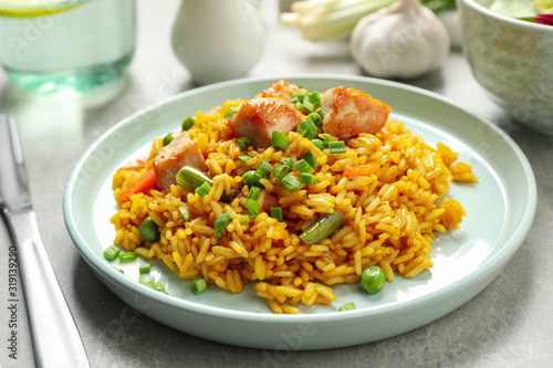 Delicious rice pilaf with vegetables and chicken on light grey table