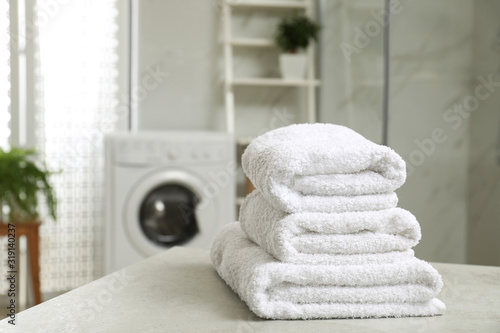 Stack of clean towels on table in laundry room. Space for text