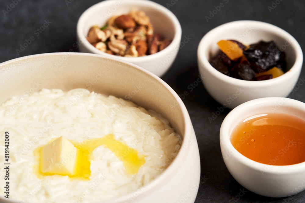 Rice porridge with milk, raisins, honey and nuts in a bowl. Rice porridge with milk, raisins, honey and nuts in a bowl.