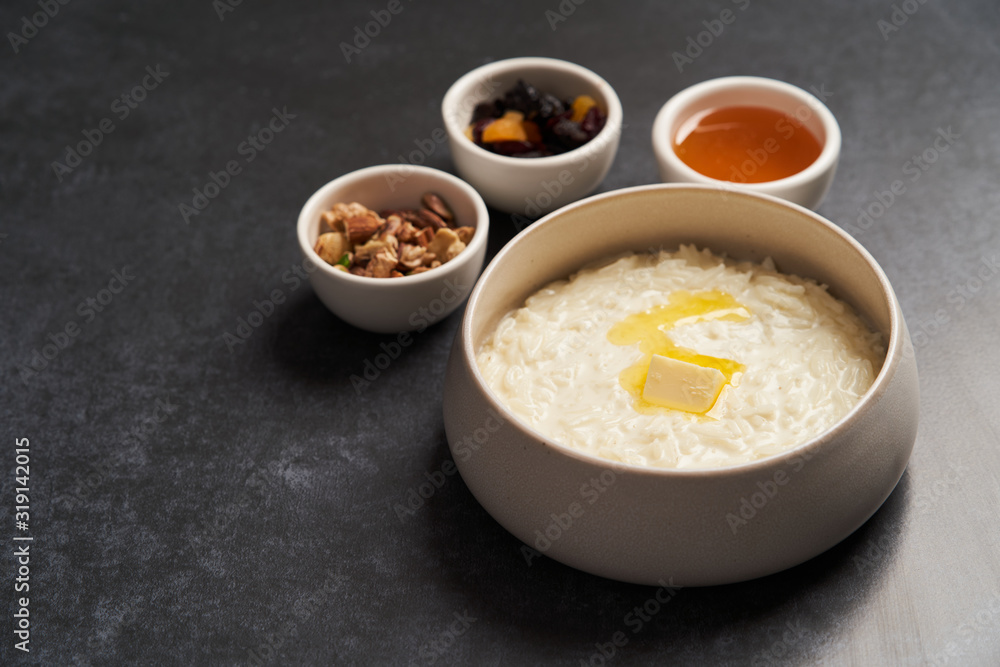 Rice porridge with milk, raisins, honey and nuts in a bowl. Rice porridge with milk, raisins, honey and nuts in a bowl.