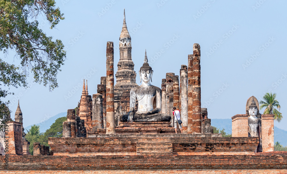 Obraz premium Tourist take pictures of ancient Buddha statue at sunrise in Ayutthaya, Thailand; travel and tourism concept