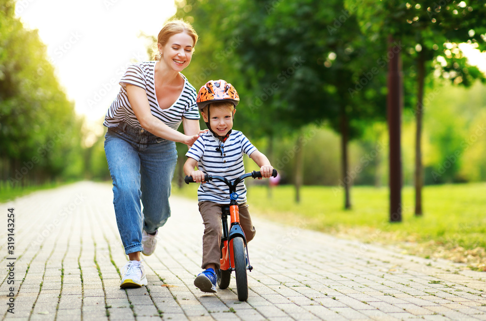 happy family mother teaches child son to ride a bike in the Park happy family mother teaches child son to ride a bike in the Park