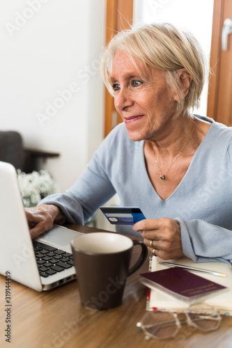 senior smiling woman buying on line with credit card vertical