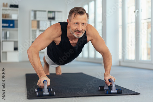 Middle-aged man exercising on handles for push-ups