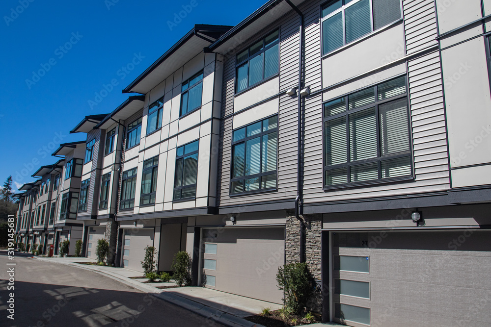 Brand new townhouse complex. Rows of townhomes side by side. External facade of a row of colorful modern urban townhouses. brand new houses just after construction on real estate market Brand new townhouse complex. Rows of townhomes side by side. External facade of a row of colorful modern urban townhouses. brand new houses just after construction on real estate market