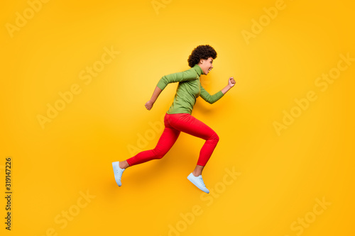 Full length body size view of her she nice attractive cheerful cheery wavy-haired girl jumping running having fun free time isolated over bright vivid shine vibrant yellow color background