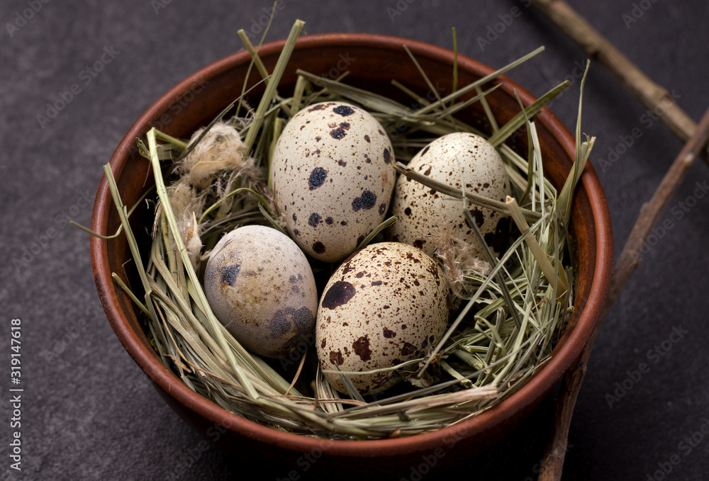 Easter quail eggs in the hay in a clay bowl close-up Easter quail eggs in the hay in a clay bowl close-up
