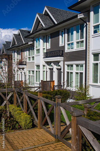 Row of new townhomes in a sidewalk neighborhood. On a sunny day in spring against bright blue sky. © Roman