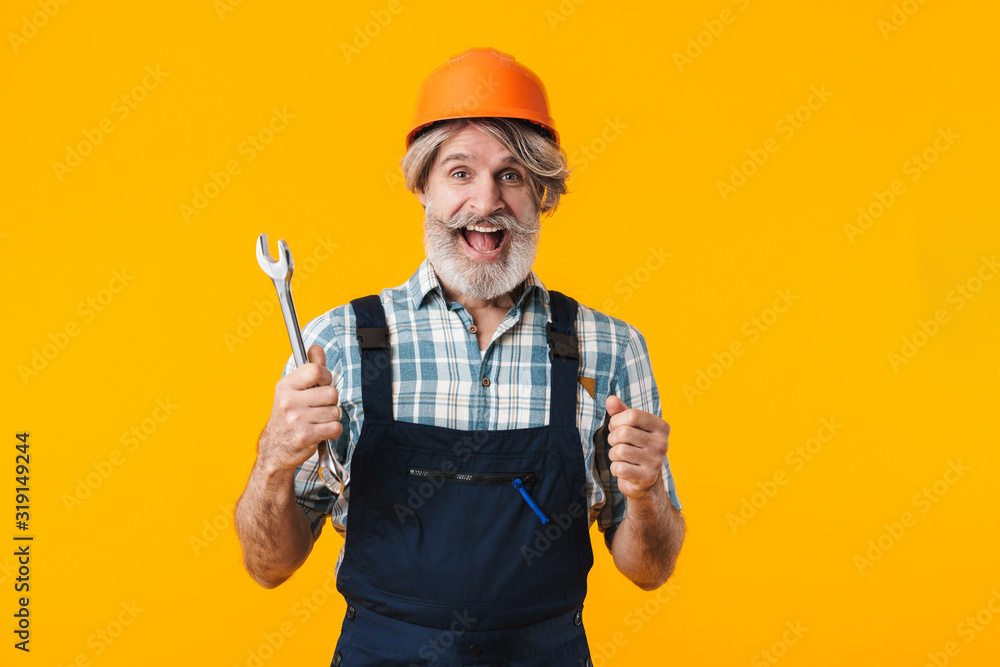 Bearded man builder in helmet holding wrench.