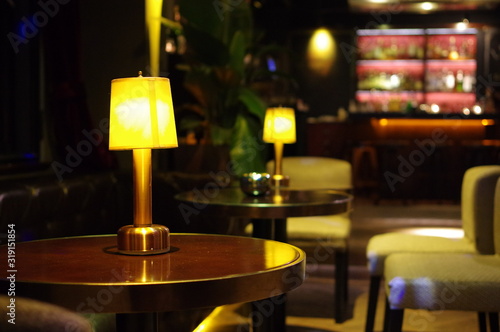 Table lamp on round bartable with gray chair and lounge counter at background