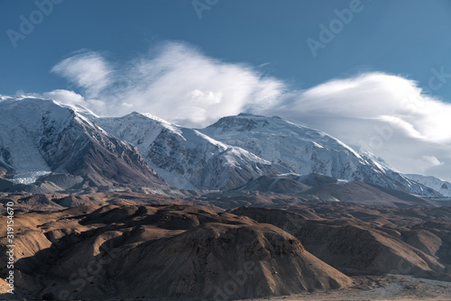 Snow mountain located in Xinjiang China Pamir Plateau in winter season. Pure blue sky and yellow sun light. © Jiva Core