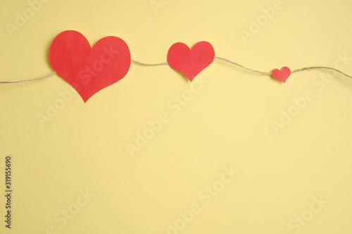 Cord of twine with red hearts on a yellow background. Top view.