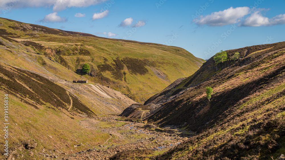 The remains of Bunton Mine with the Gunnerside Gill landscape, near Gunnerside, North Yorkshire, England, UK