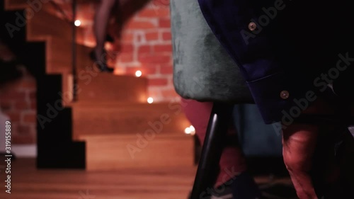 Man tied to a chair close up. Female walking down the stairs on high heels. Romantic scene and atmosphere.
