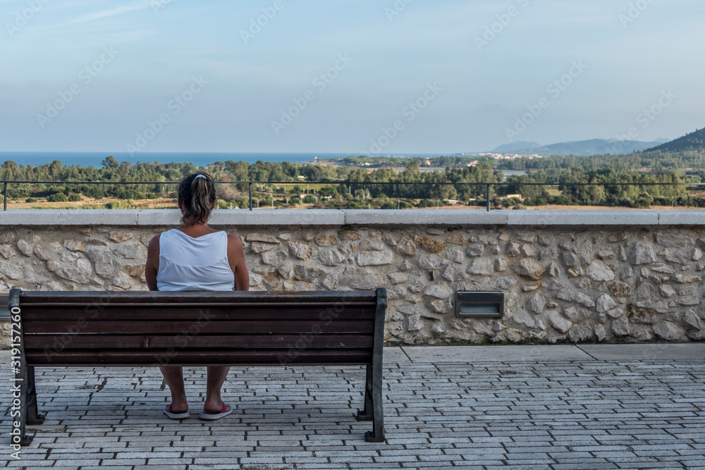 woman sitting on a bench looks at the view in Posada