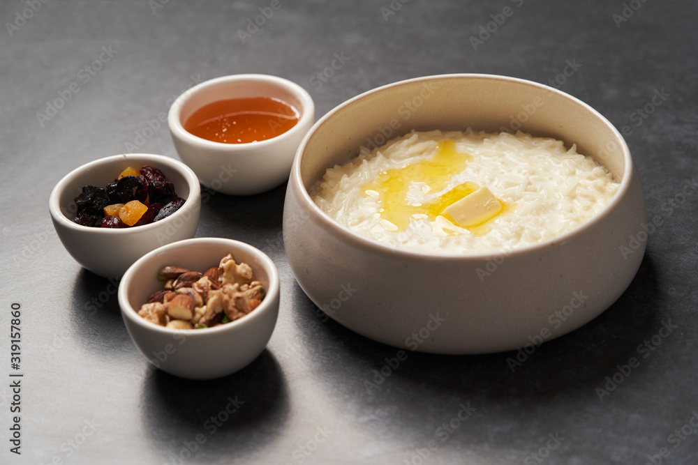Rice porridge with milk, raisins, honey and nuts in a bowl. Rice porridge with milk, raisins, honey and nuts in a bowl.
