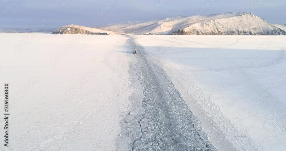 Drone Rises Above Trail Left by a Boat on the Ice of a Frozen Lake. Winter Landscape Aerial Shot Top View Icebreaker on Surface of Lake Baikal. Drone Rises Above Trail Left by a Boat on the Ice of a Frozen Lake. Winter Landscape Aerial Shot Top View Icebreaker on Surface of Lake Baikal.