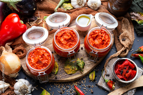 Colorful tabletop scene with raw ajvar surrounded with vegetables. Vegan chutney flat lay scene. Healthy eating