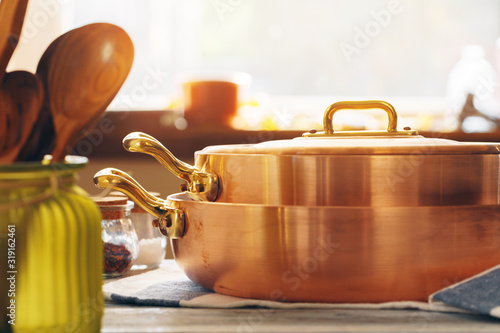 Copper cookware with wooden kitchen utensils close up photo