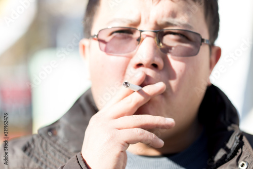 Closeup of a handsome young man smoking a cigarette outdoors