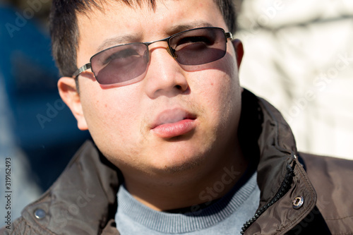 Closeup of a handsome young man smoking a cigarette outdoors