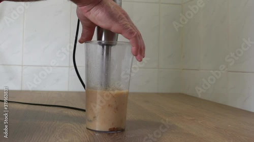 man in the kitchen making sauce with hand blender. On a free table with white background