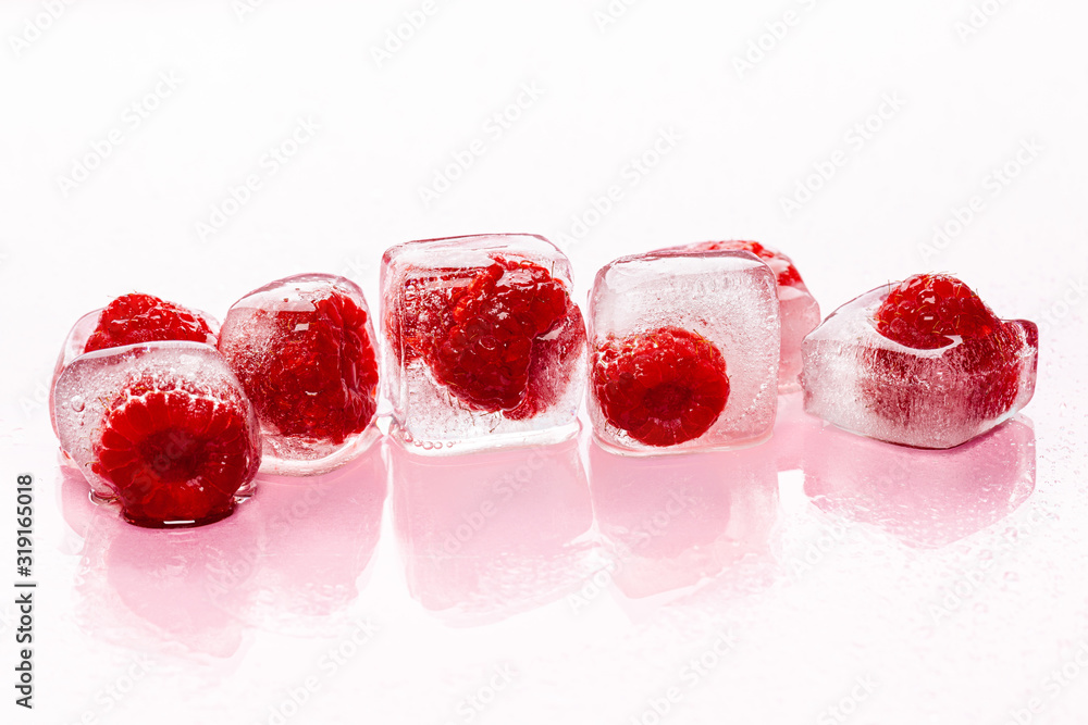 Raspberry ice cubes on pink glossy background
