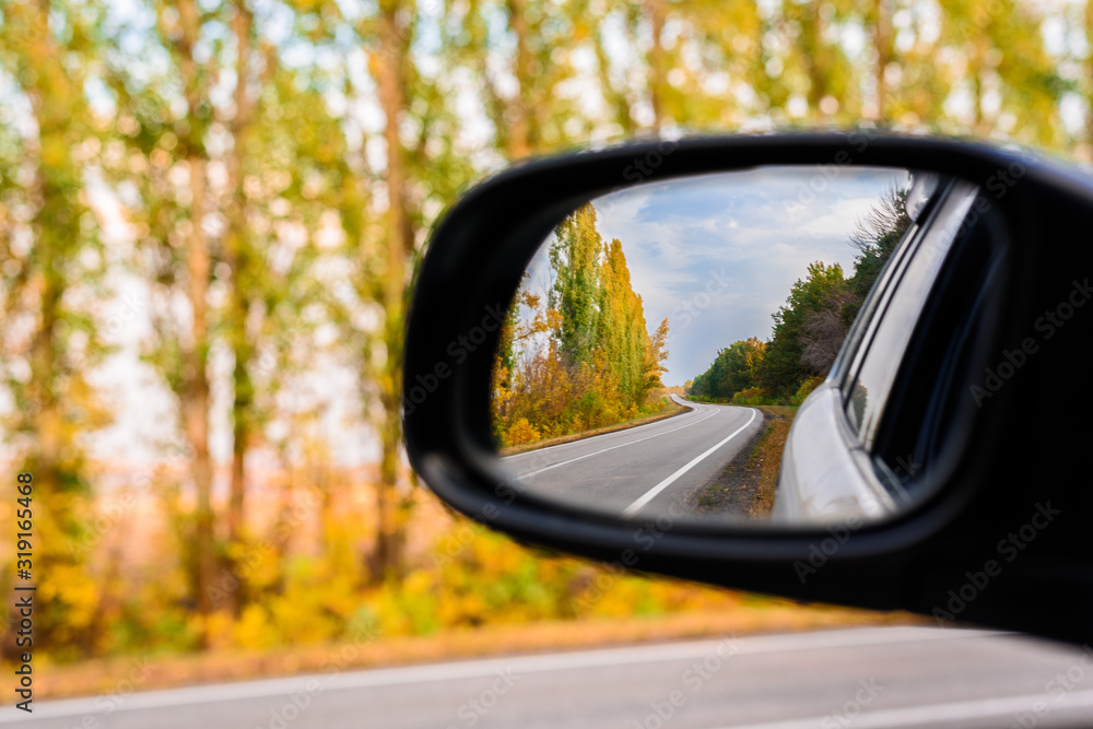 autumn landscape is reflected in the car mirror . cities that go into the distance