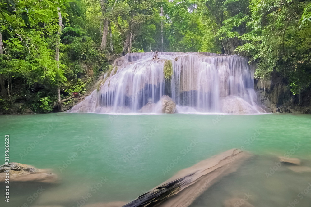Beautiful silky water flowing on cliff rock around with blue-green water and green forest background, Erawan waterfalls 2th step, Kanchanaburi, west of Thailand.