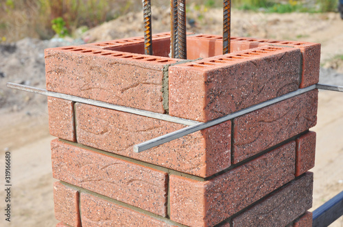 Obraz na plátně Bricklaying column from red brick blocks with metal rod