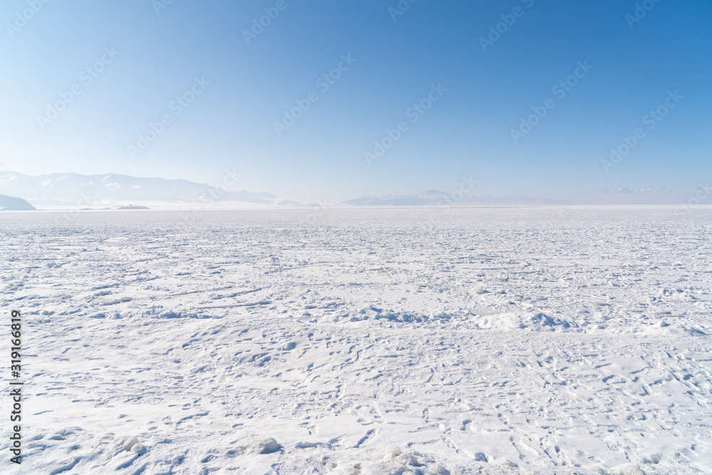 Snow covered frozen ice lake located in Xinjiang China Sayram lake. Winter season.