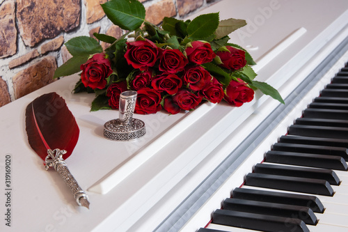Old vintage feather for writing love letters  with roses on a piano