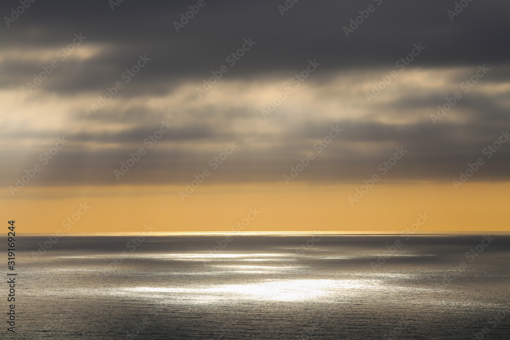 Leaden clouds and rays of the sun through them over the ocean Leaden clouds and rays of the sun through them over the ocean