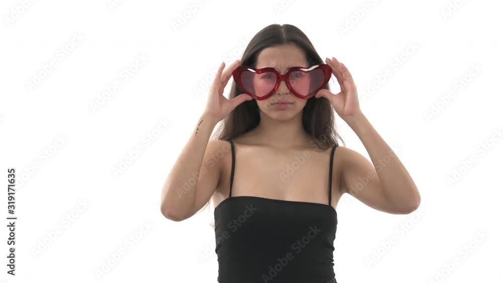Gorgeous Caucasian woman takes off heart shaped glasses and looking into distance. Smiling woman. Isolated, on white background Gorgeous Caucasian woman takes off heart shaped glasses and looking into distance. Smiling woman. Isolated, on white background