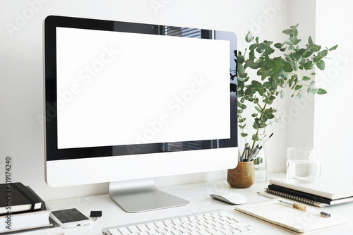 Side view of stylish modern workspace in light room. Generic desktop computer with blank white display with copy space for your design, text, information and advertising content. Nobody around