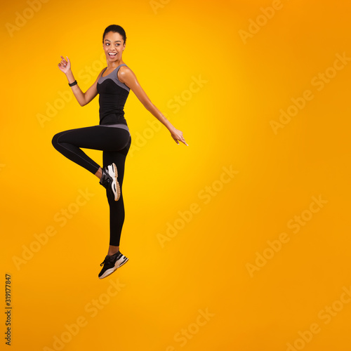 African American Lady Jumping Over Yellow Studio Background