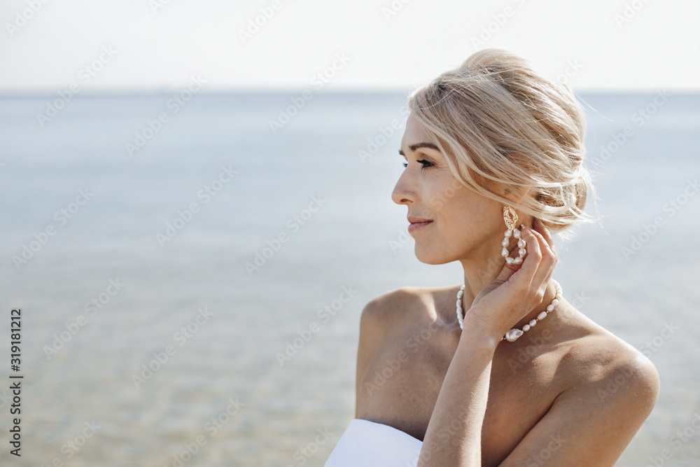 Portrait of beautiful blonde caucasian woman on the sunny day near the sea