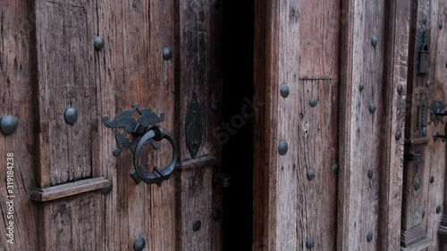 Close-up of closing old wooden door with metal handle in ancient medieval Catholic church. For religion, histotic, architecture background.