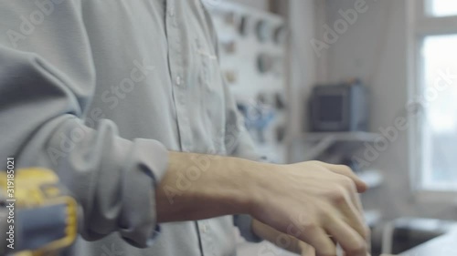 Close-up shot of hands of anonymous male carpenter joining together wooden furniture components with mortise and tenon joint and pressing down against worktop