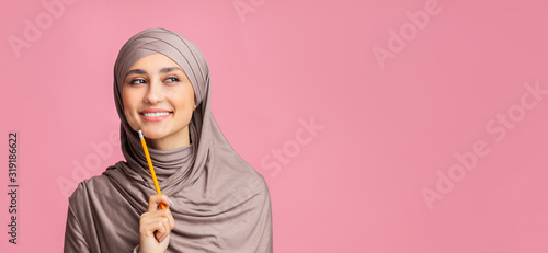 Pensive muslim woman in headscarf holding pencil, overthinking about something