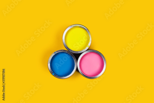 Renovation picture. Yellow background with three paint cans. Flat lay, top view, copy space.