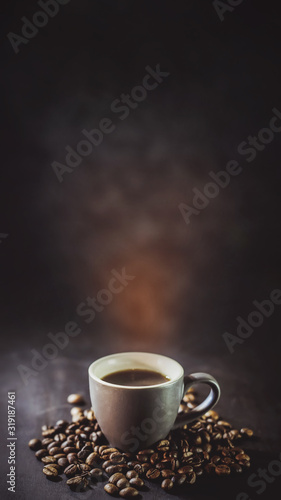  cup of coffee and coffee grains with smoke on a dark background.