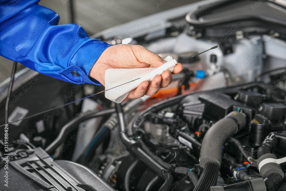 Male mechanic checking level of oil in car engine Male mechanic checking level of oil in car engine